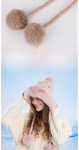 Dettaglio del cappello invernale rosa con bordo in ecopelliccia e doppi pompon soffici
