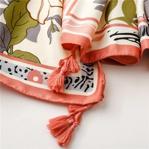 Detail of silk scarf showing tropical leaf patterns and coral pink tassel fringe edges