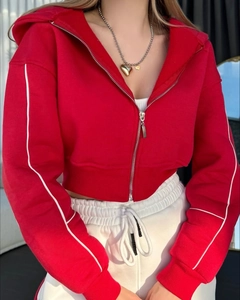 Détail d'un sweat à capuche court rouge avec rayure blanche et collier cœur doré