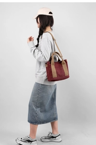 Detail of burgundy canvas tote bag featuring khaki straps and adjustable shoulder strap