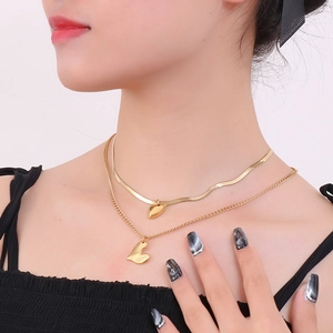 Close-up of double-layer gold heart necklace with snake chain on model's neckline