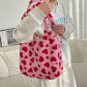 Close-up of soft pink plush tote bag with red heart patterns and interior quality label