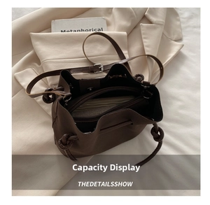 Internal view of dark brown bucket bag showing central zipper and spacious compartment