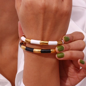Detailed view of bamboo-style enamel bangles in black and white with gold accents