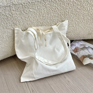 Detail of white canvas tote bag with drawstring texture on a cream boucle sofa