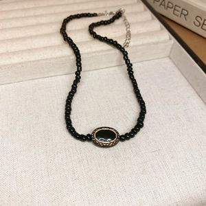 Detail of beaded necklace with black oval pendant and gold vintage pattern on jewelry box