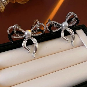 Macro shot of bow-knot pearl earrings with sparkling crystals on a leather jewelry box