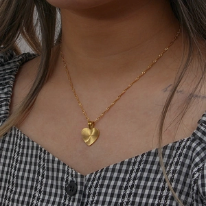 Close-up of golden heart pendant with radial texture and 18K gold plated chain