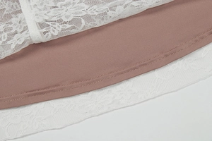 Detail van wit bloemenkant en roze voering bij de zoom van de jurk met V-halslijn
