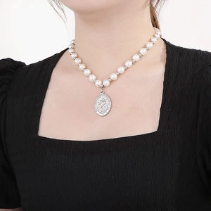 Détail de la médaille Saint Christophe sur collier de perles avec pendentif argenté
