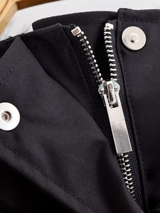 Detailed macro view of high-quality silver metal zipper and snaps on black jacket fabric