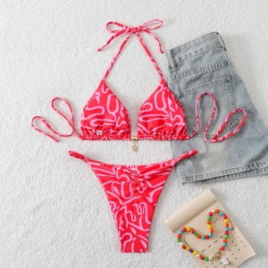 Flat lay of pink and red bikini set with star pendant on white plush background
