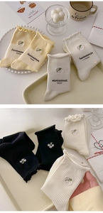 Detail of cream cotton socks with ruffled edges and small floral embroidery designs