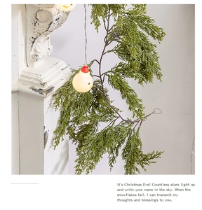 Detail of Christmas snowman LED string lights intertwined with green pine needle garland