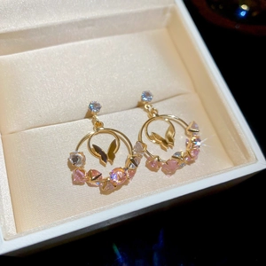 Detail of gold butterfly drop earrings with pink zircons in a velvet jewelry box