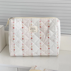 Detail of fabric makeup bag with floral print and diamond stitching on white background