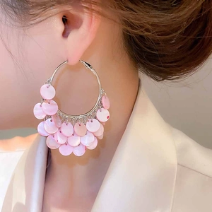 Close-up of geometric pink sequin hoop earrings with iridescent shell-like finish