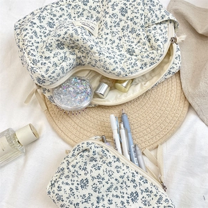 Detail of floral quilted cosmetic bag with blue begonia pattern and zipper closure