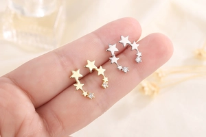 Detail of silver and gold triple star stud earrings with zirconia held by hand