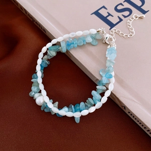 Detail eines zweischichtigen Armbands mit blauen Steinen und Perlen auf lässigem Hintergrund