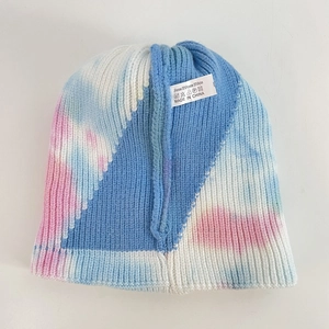 Detail view of tie-dye knit beanie material label showing fabric composition and texture