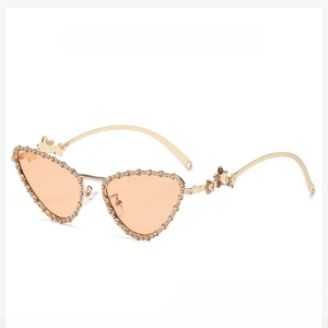 Detail of golden cat-eye sunglasses with orange lenses and star-shaped temple accents