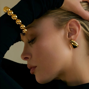 Polished 18k gold plated stainless steel geometric trapezoid earrings worn by a model