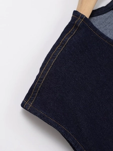 Detailed close-up of dark blue denim dress featuring yellow double decorative stitching