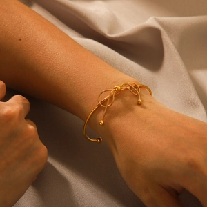 18K gold stainless steel bow cuff bracelet with beads on female model's wrist