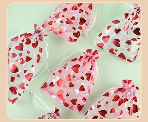 Detailed view of pink organza gift bags with red heart patterns and drawstring closures