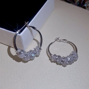 Detail shot of silver entwined hoop earrings with sparkling crystal accents in a white box