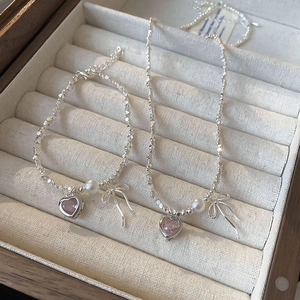 Detail of silver necklace set with pink zircon heart and bow in jewelry box
