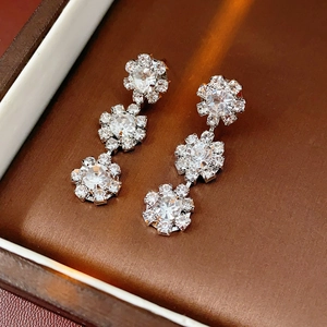 Detail view of silver sunflower drop earrings with sparkling crystals in a jewelry box