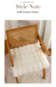 Dettaglio del cuscino spesso in peluche color crema su una sedia di legno per la casa