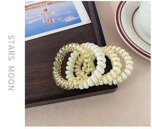 Close-up of four colorful spiral hair ties on a wooden tray with a minimal background