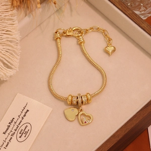 Detailed close-up of 18K gold-plated heart charms and cubic zirconia on a snake chain