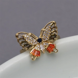 Artistic golden butterfly ring with colorful zircons and blue center stone on ceramic edge