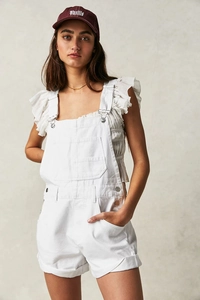 Detail of white denim overall shorts showing classic chest pocket and metal buttons