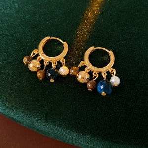 Detailed macro view of vintage gold hoop earrings with pearl and tiger eye bead charms