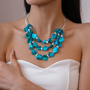 Detail of layered bohemian necklace with turquoise beads and shell charms on model
