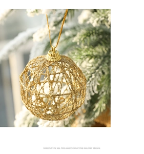 Golden iron glitter hollow Christmas ball hanging on a snowy festive tree branch