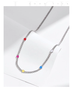 Macro detail of silver necklace featuring five colorful heart pendants with soft shadows