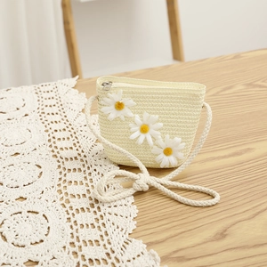 Detail of a straw woven bag with white daisy decor and a thick rope strap on lace