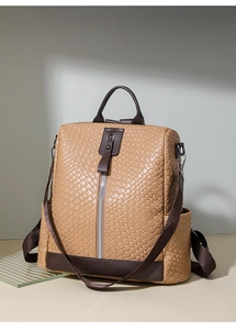 Detail showing the brown woven leather texture and vertical zipper on the backpack
