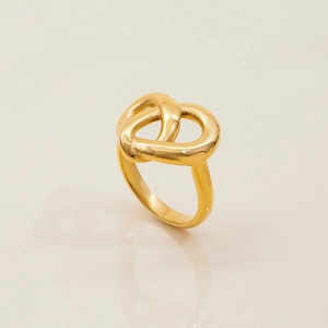 Close-up of a vintage 18K gold-plated stainless steel knot ring on a beige surface