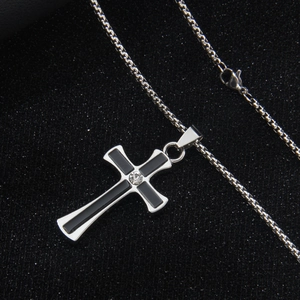 Silver stainless steel cross necklace with black inlay and crystal on dark background