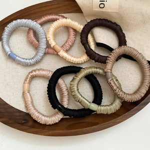 Eight-piece set of pleated silk hair ties in neutral Morandi colors on a wooden tray