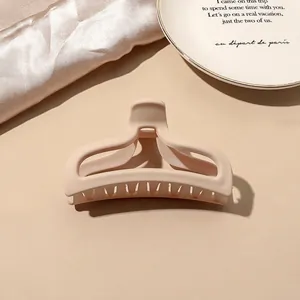Macro shot of a matte beige arch-shaped hair claw clip on soft silk fabric background