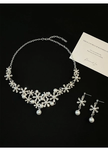 Detailed set of floral silver necklace and pearl earrings over a black background
