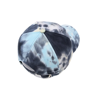 Detail view of tie-dye baseball cap featuring distressed holes and metal adjustment buckle